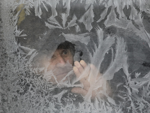 Man looks through frosted bus window with air temperature at about minus 16 degrees Celsius in Lviv
