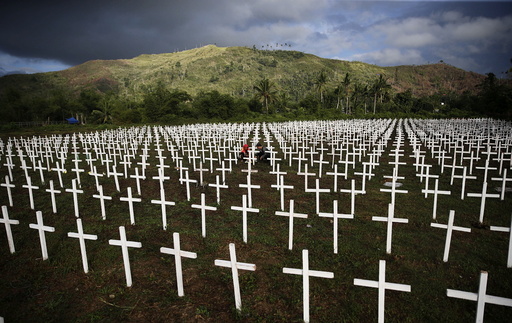 A couple visiting the graves of their four children is seen among thousands of crosses at a mass grave for Typhoon Haiyan victims on All Saints Day in Tacloban city in central Philippines