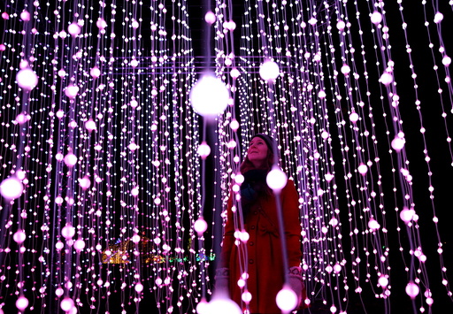 A woman poses amongst illuminations at photo-call for the Christmas at Kew Festival in London, Britain
