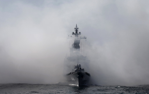 JMSDF destroyer Kurama, which is carrying Japan's PM Abe, sails in smoke during its fleet review at Sagami Bay, off Yokosuka