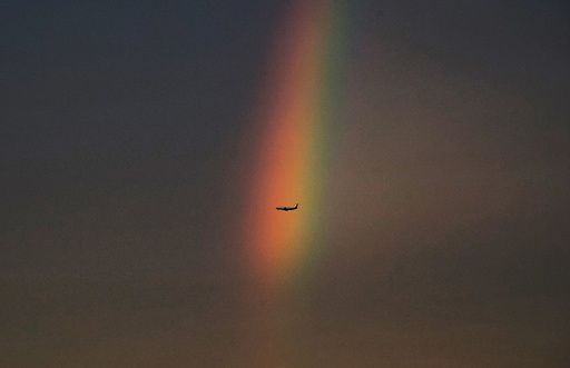 An airplane flies past a rainbow at dusk in Beijing