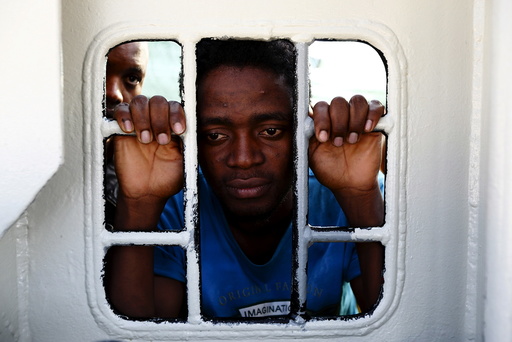 Migrants look out of a window on the Medecins Sans Frontiere (MSF) rescue ship Bourbon Argos as it arrives in Trapani, on the island of Sicily