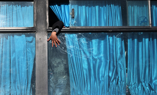 A Palestinian boy puts his hand out of a bus window as he waits with his family to cross into Egypt through the Rafah border crossing after it was opened by Egyptian authorities for humanitarian cases, in Rafah in the southern Gaza Strip