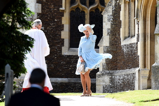 Camilla, the Duchess of Cornwall, controls her skirts as a gust of wind blows while she arrives at the Church of St Mary Magdalene on the Sandringham Estate for the christening of Princess Charlotte