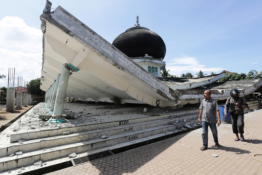 People walk near a collapsed mosque following an earthquake in Meuredu, Pidie Jaya in the northern province of Aceh