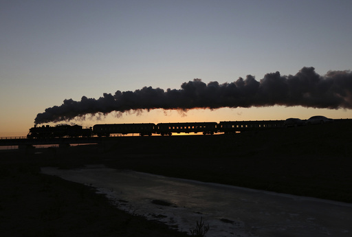 A steam train travels among crop fields at the annual steam train festival during sunrise in Diaobingshan