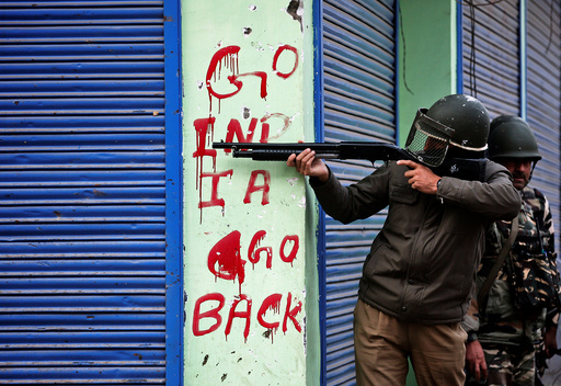 An Indian policeman aims his gun during an anti-India protest in Srinagar