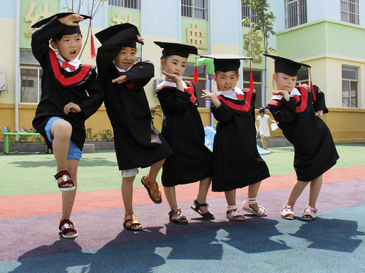 Children in gowns and mortarboards pose for pictures during their kindergarten graduation ceremony, in Wenxian county