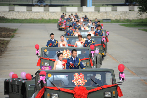 Soldiers of China's Liberation Army (PLA) air force stand on military vehicles as they attend a group wedding in Anshan