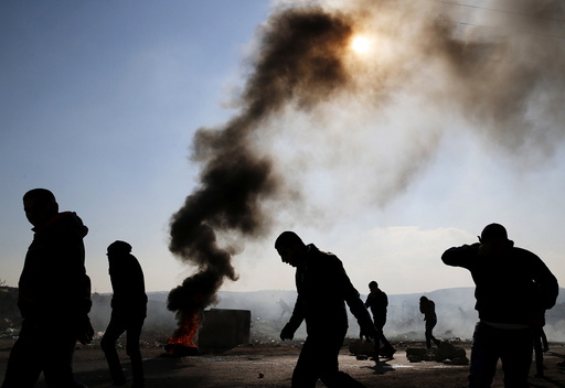 Palestinian protesters react to teargas fired by Israeli troops during clashes in the West Bank village of Silwad, near Ramallah