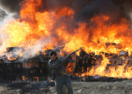 An Afghan officer reacts in front of a burning pile of seized narcotics and alcoholic drinks, in the outskirts of Kabul