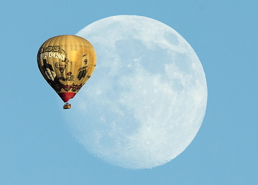 A hot air ballon floats past a rising moon over Rancho Santa Fe, California
