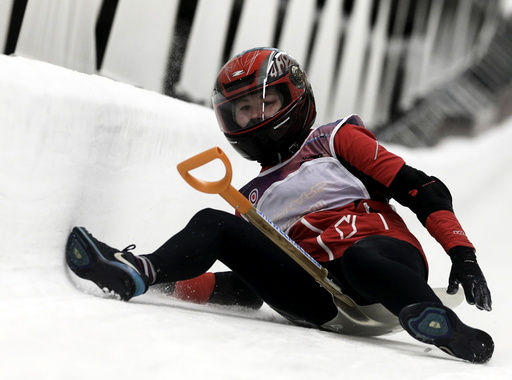 A woman slides down during the shovel race event on the luge and bobsleigh track in Sigulda