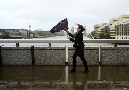 A commuter loses control of her umbrella as she braves the wind and rain while crossing London Bridge in London