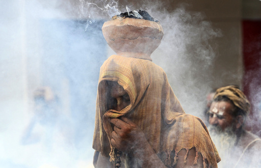 A Sadhu covers his face as an earthen pot with burning Upale rests on his head during a prayer ceremony at the Simhastha Kumbh Mela in Ujjain