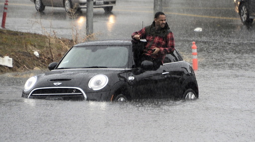 A driver climbs out of a window of his car after driving onto a flooded road in Van Nuys
