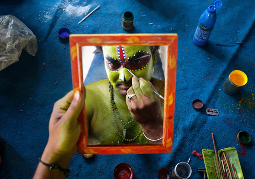 An artiste is reflected in a mirror as he applies make-up backstage before taking part in a celebration to mark Hindu festival of Ramnavami inside the premises of a temple in Bengaluru