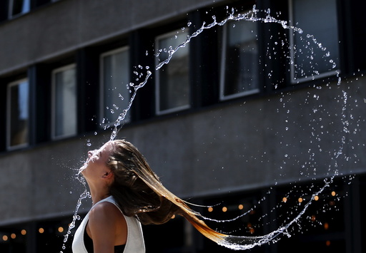 A woman swings her hair back after dipping her head into a fountain in Budapest