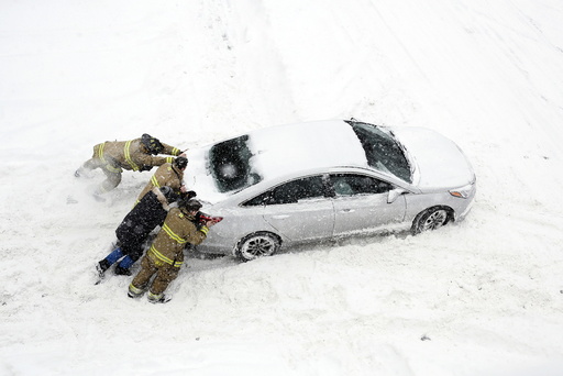 Firefighters help push a car stuck in snow during a winter storm in Ottawa