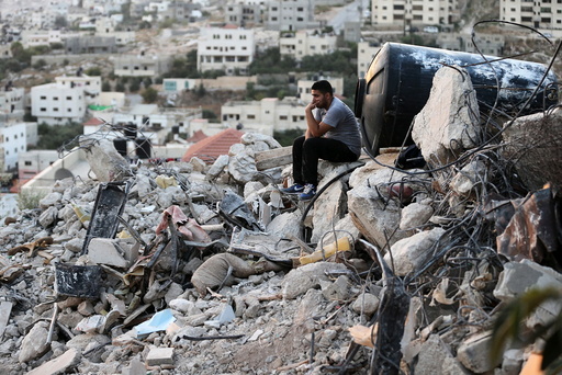 A Palestinian man sits atop the rubble of a house which was destroyed by Israeli troops during an Israeli raid in the West Bank city of Jenin