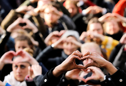 People make hearts with their fingers during a ceremony outside the Bourse, commemorating the first anniversary of the bomb attacks in Brussels metro and the Belgian international airport of Zaventem, in Brussels