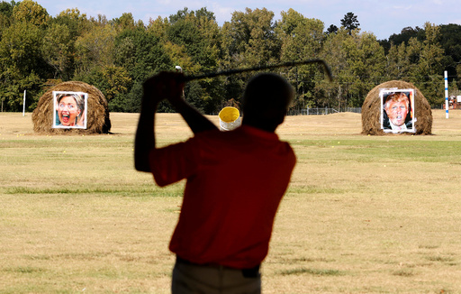 Mike Williams, owner of the Alpine Target Golf Center, shows off his swing at a driving range with hay bales covered with the portraits of U.S. presidential nominees Hillary Clinton and Donald Trump