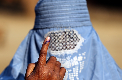 A woman shows her ink marked finger after voting during the state assembly election, in the village of Kairana, in the state of Uttar Pradesh