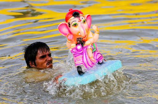 A man immerses an idol of Hindu god Ganesh, the deity of prosperity, in a pond on the second day of Ganesh Chaturthi festival in Ahmedabad