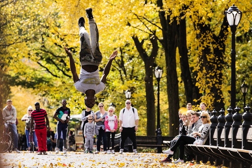 A street performer jumps in the air inside Central Park as the colors of autumn become more prevalent in New York