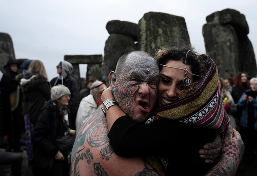 Visitors and revellers react amongst the prehistoric stones of the Stonehenge monument at dawn on Winter Solstice, near Amesbury