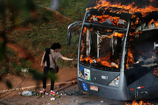 A man lights up his cigarette with the flames of a bus burned by anti-government demonstrators during a protest against the constitutional amendment PEC 55, which limits public spending, in front of Brazil's National Congress in Brasilia