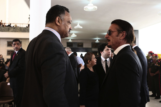 Civil rights leader Rev. Jesse Jackson Sr. talks with actor Sean Penn during the funeral for Venezuela's late President Hugo Chavez in Caracas