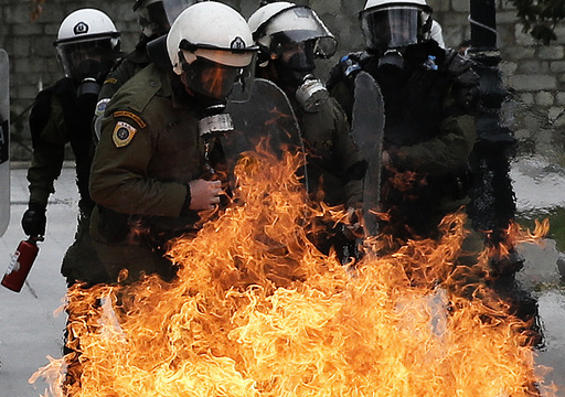 Riot police react to petrol bombs thrown by masked youths in Syntagma Square during a 24-hour general strike against planned pension reforms in Athens