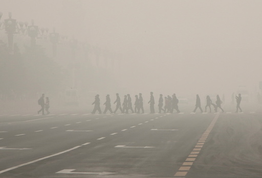 Pedestrians and policeman cross the street at a crosswalk at the Tiananmen Square during a heavily polluted day in Beijing