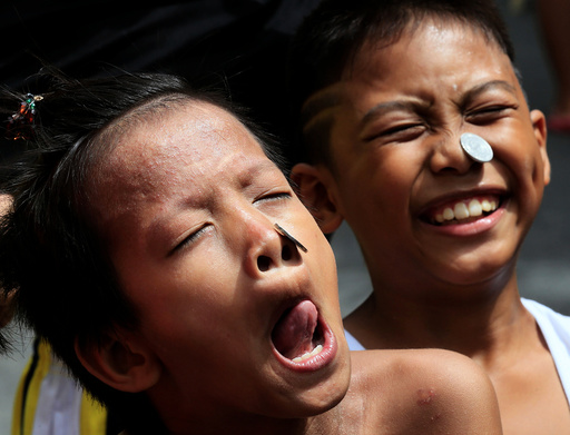 Boys use their face and tongue to move a coin from their forehead into their mouth while participating in a parlour game during a religious festival in Paranaque City