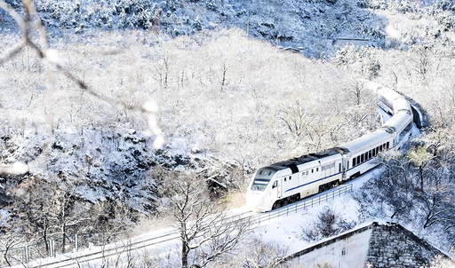 A train travels through hills covered by snow after heavy snowfall on the outskirts of Beijing