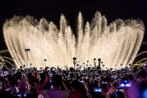People record a water fountain show with their mobile phones in Hangzhou