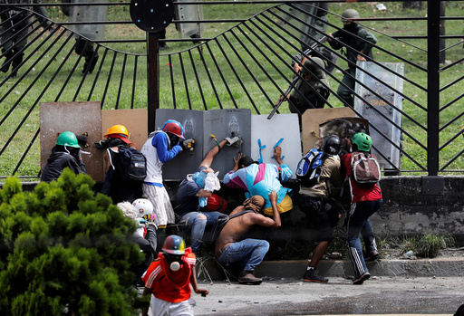 Demonstrators clash with riot security forces at the fence of an air base while rallying against Venezuela's President Nicolas Maduro in Caracas
