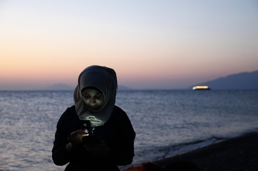 A Syrian refugee sends text messages to relatives moments after arriving at a beach on the Greek island of Kos