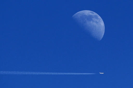 An aircraft flies past the moon over Ardales,near Malaga, southern Spain