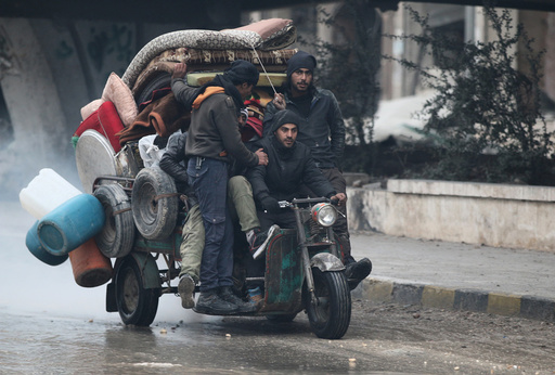 Men ride a tricycle as they flee deeper into the remaining rebel-held areas of Aleppo
