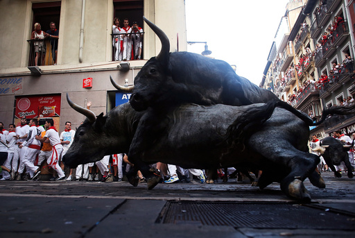 Jose Escolar Gil fighting bulls fall on top of each other at Estafeta corner during the third running of the bulls at the San Fermin festival in Pamplona