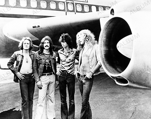 Led Zeppelin stands beneath wing of their plane Starhip One. (1-r) John Paul Jones, John Bonham, Jimmy Page, Robert Plant. July 1973.