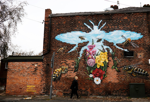 A woman walks past steet art showing bees, the city's symbol, in Manchester
