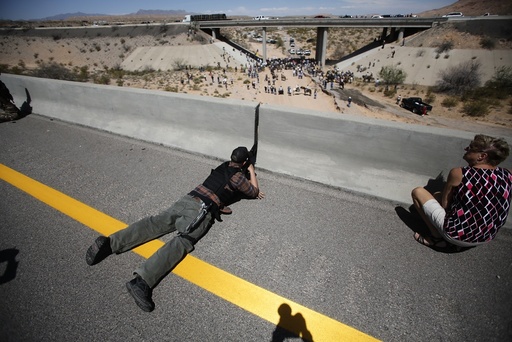 Parker from central Idaho aims his weapon from a bridge as protesters gather by the Bureau of Land Management's base camp near Bunkerville