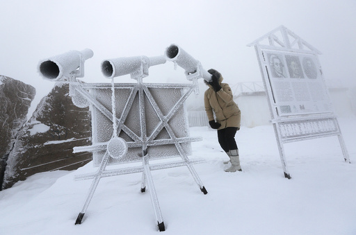 A woman looks through a telescope covered with hoarfrost near Krasnoyarsk