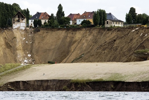 A crumbling house sits on the edge of a cliff following a landslide in the village of Nachterstedt