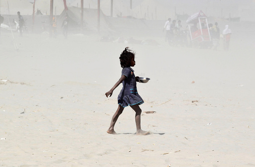 A girl walks amidst a dust storm on the banks of the Ganges river in Allahabad