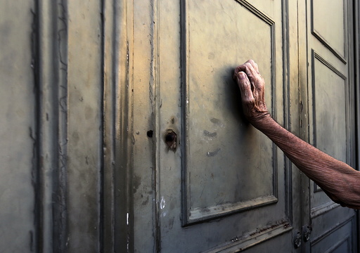A pensioner leans against the main door of a branch of the National Bank in Athens