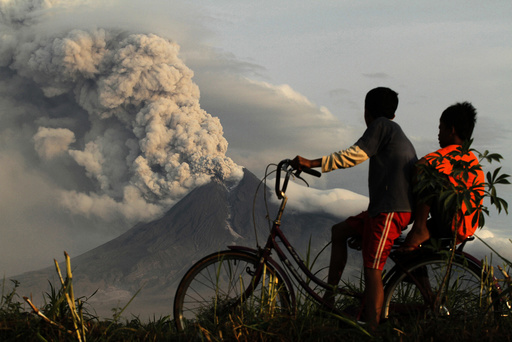 Boys look at the eruption of Mount Merapi volcano in Manisrenggo village